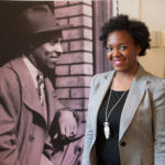 Dominique Luster standing next to a photo of Teenie Harris
