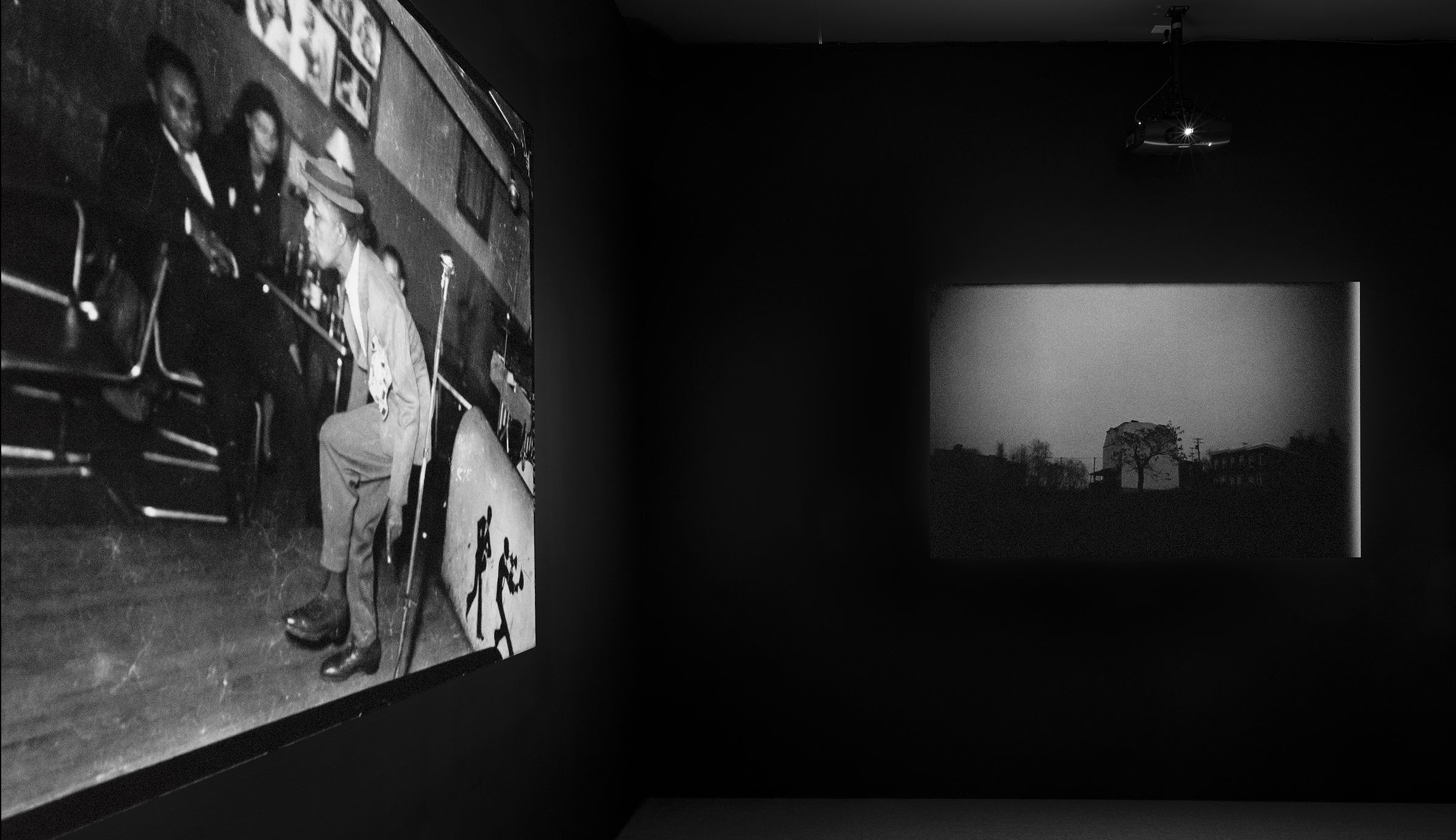 Installation view of REkOGNIZE showing images and videos projected onto walls in a dark room 