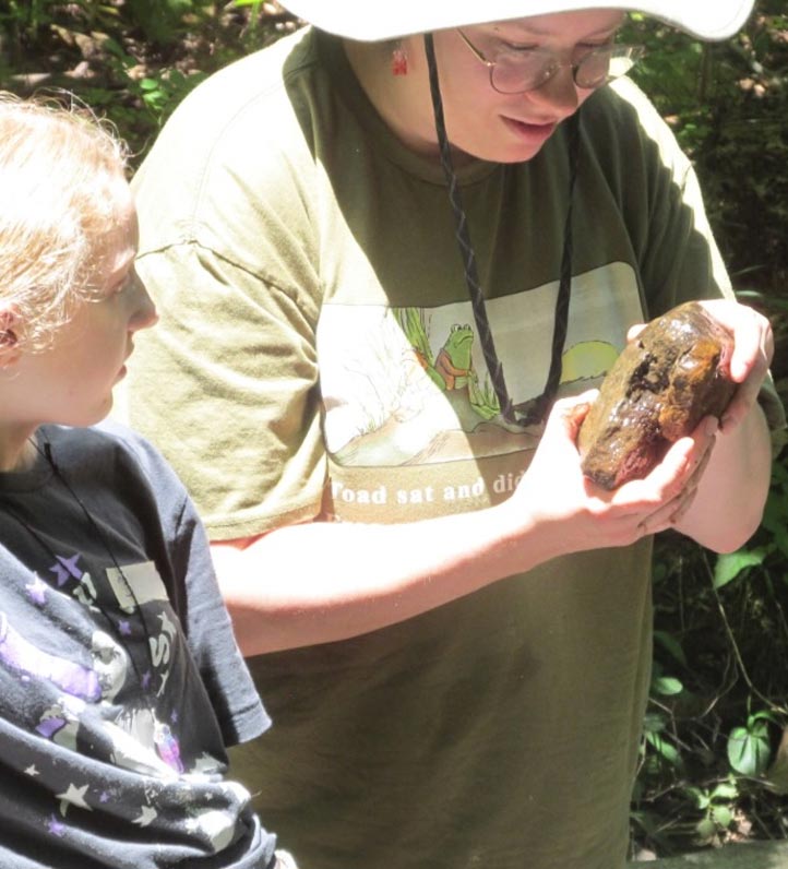 A scientist showing a wet river rock to a student