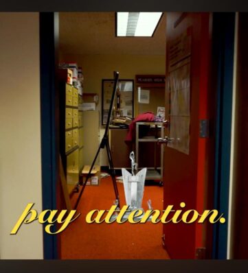 A doorway reveals a cluttered office with a sign that reads "pay attention," emphasizing a call to focus amid the chaos.