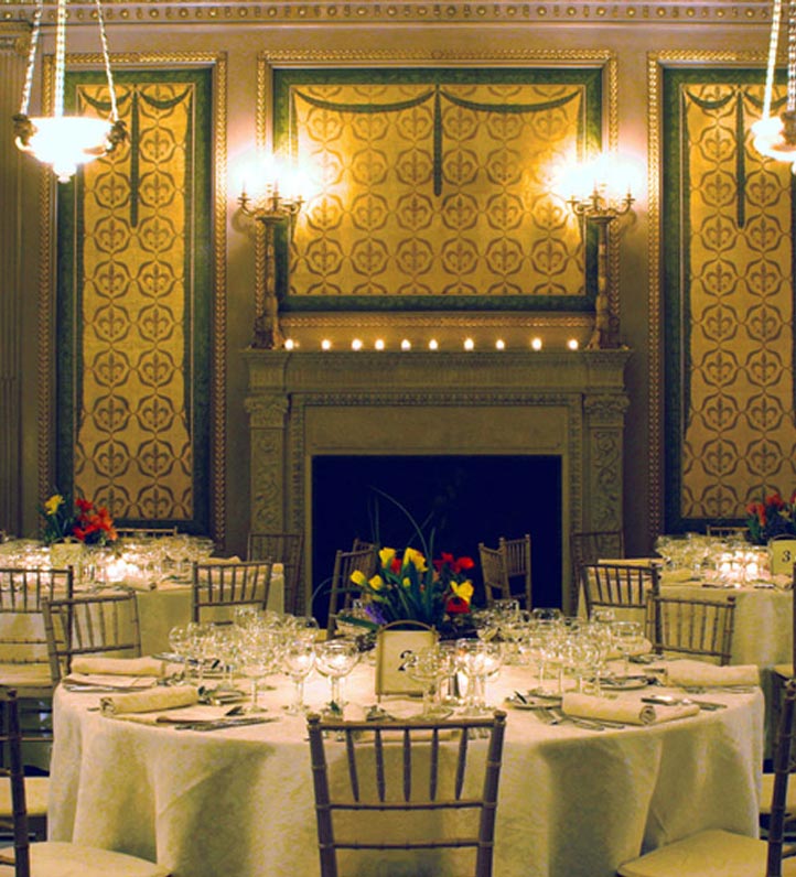 A fancy room with a table set for a meal with tablecloths and glasses.