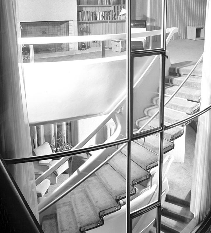 a carpeted, curved staircase seen through a glass window.