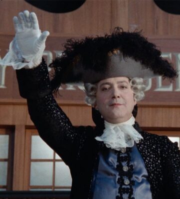 a man in historical costume with lace at the sleeve and neck and a feathered tricorn hat