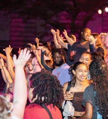 A lively crowd at Inside Out, with people dancing and celebrating joyfully under colorful lights.