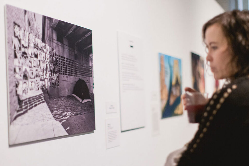A woman in a black sweater looking at a photo on the wall of a museum