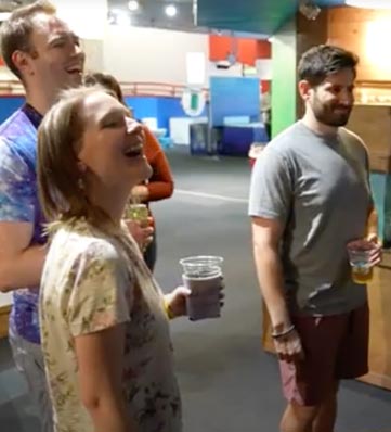 young adults carrying drinks enjoy a laugh at the science center