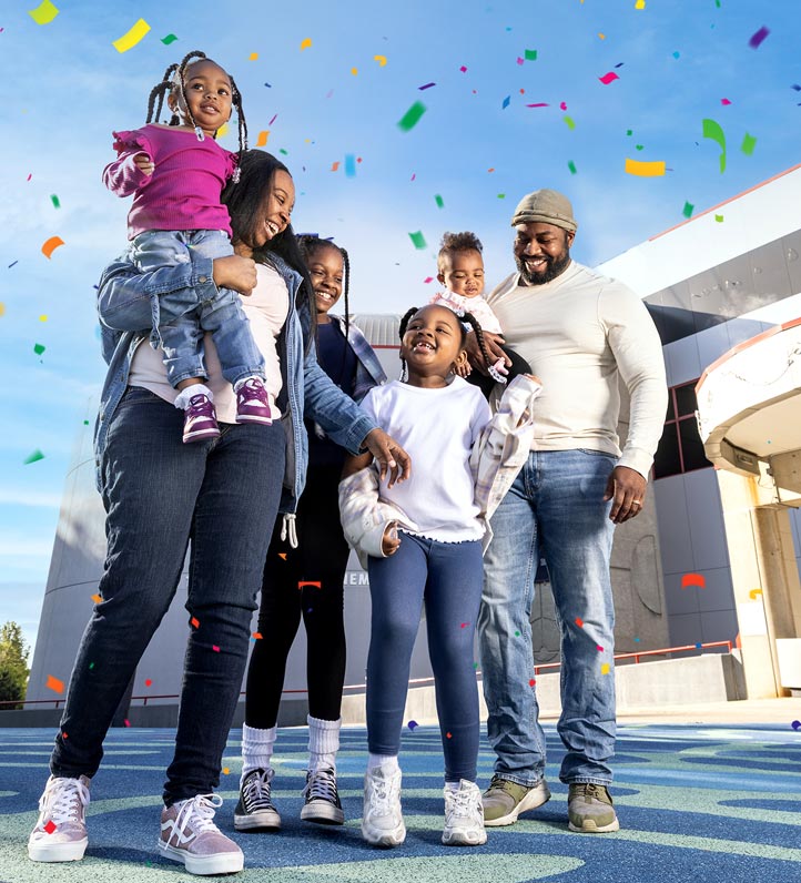 A happy family in front of the science center with confetti falling