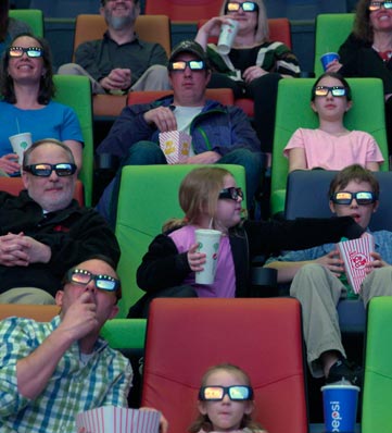 A crowd of moviegoers sitting in colorful theater seats, enjoying snacks and drinks in a vibrant cinema setting.