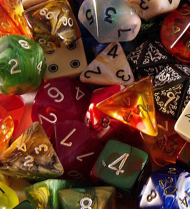 A colorful assortment of various gaming dice, including d6, d20, and others, scattered together on a light surface.