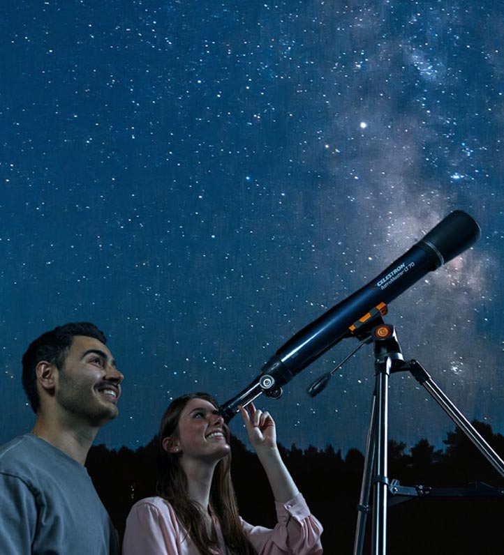A couple gazes at the starry night sky, using a telescope to explore celestial wonders amidst a backdrop of twinkling stars.