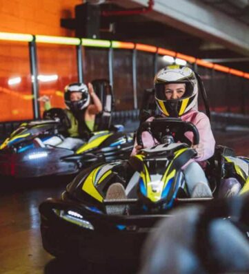 adults wearing helmets driving go-carts
