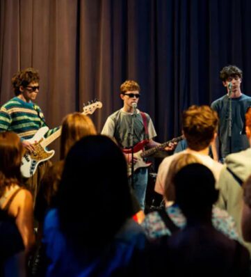 teens jamming out on a stage with a teen audience.
