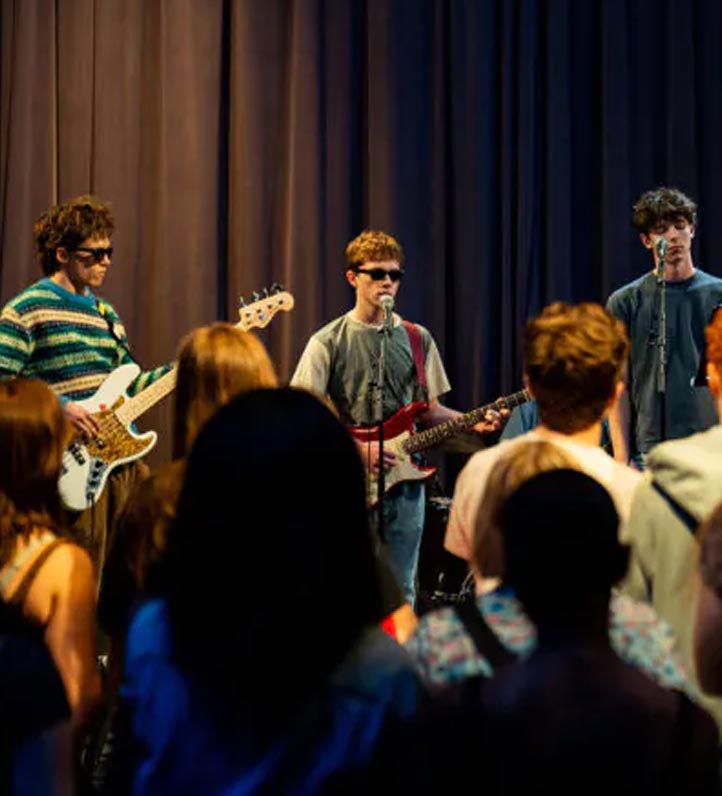 teens jamming out on a stage with a teen audience.