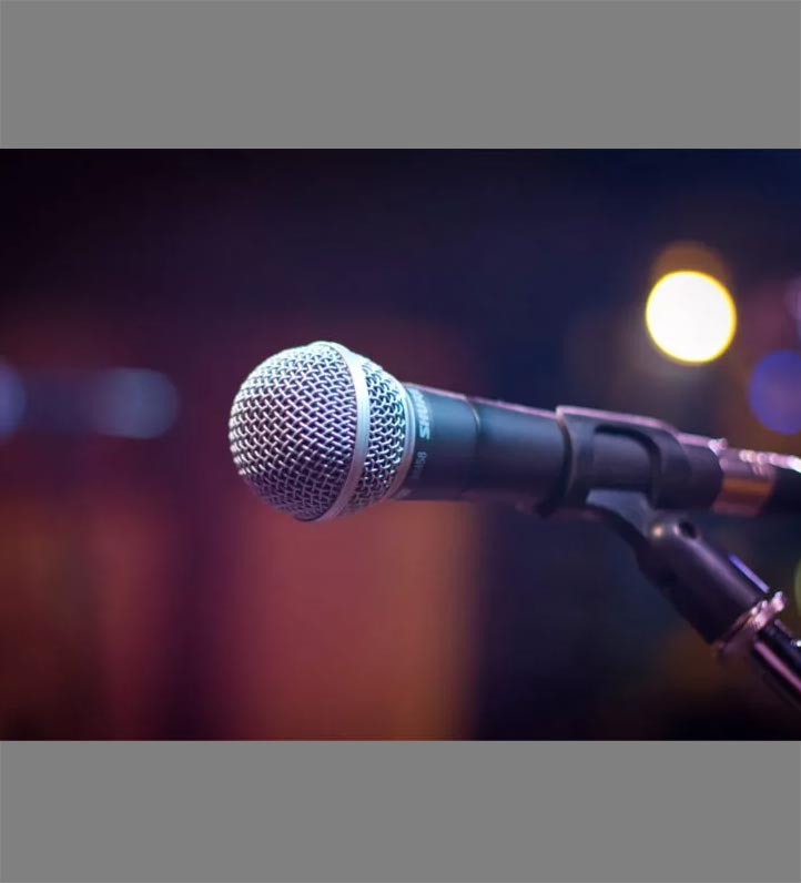 Close-up of a silver microphone on a stand, with colorful bokeh lights in the background, creating a vibrant atmosphere.