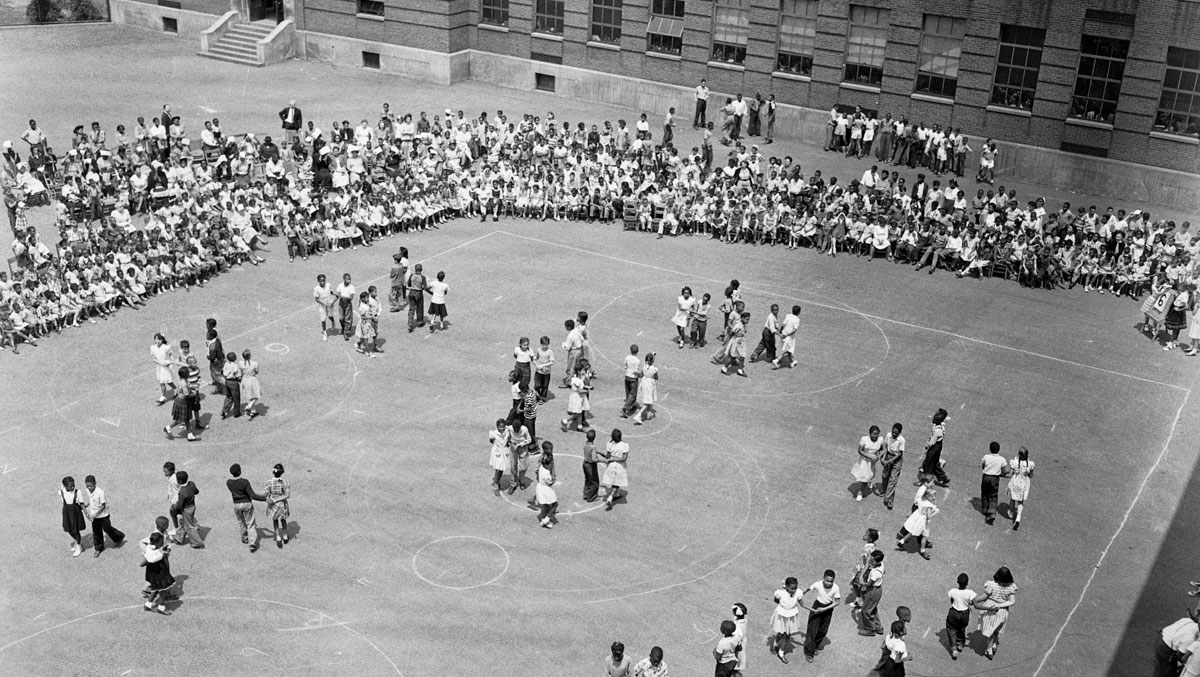 black and white photo of school children giving square dancing demonstration in a school yard