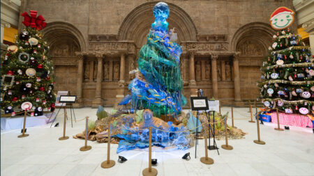 three colorfully decorated christmas trees in a museum setting