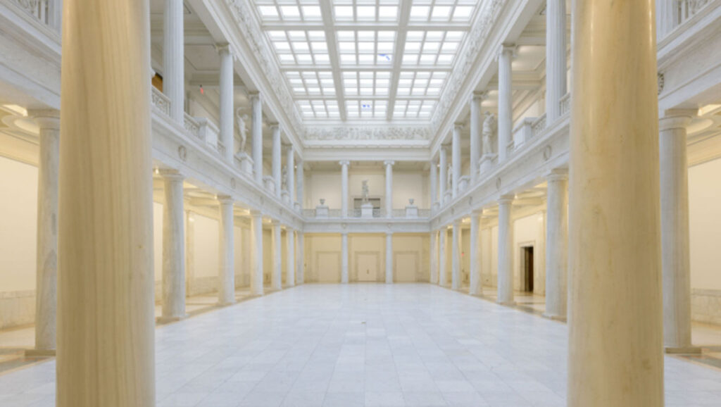 Spacious, elegant interior of a marble hall featuring tall columns and a skylight, creating a bright, open ambiance.