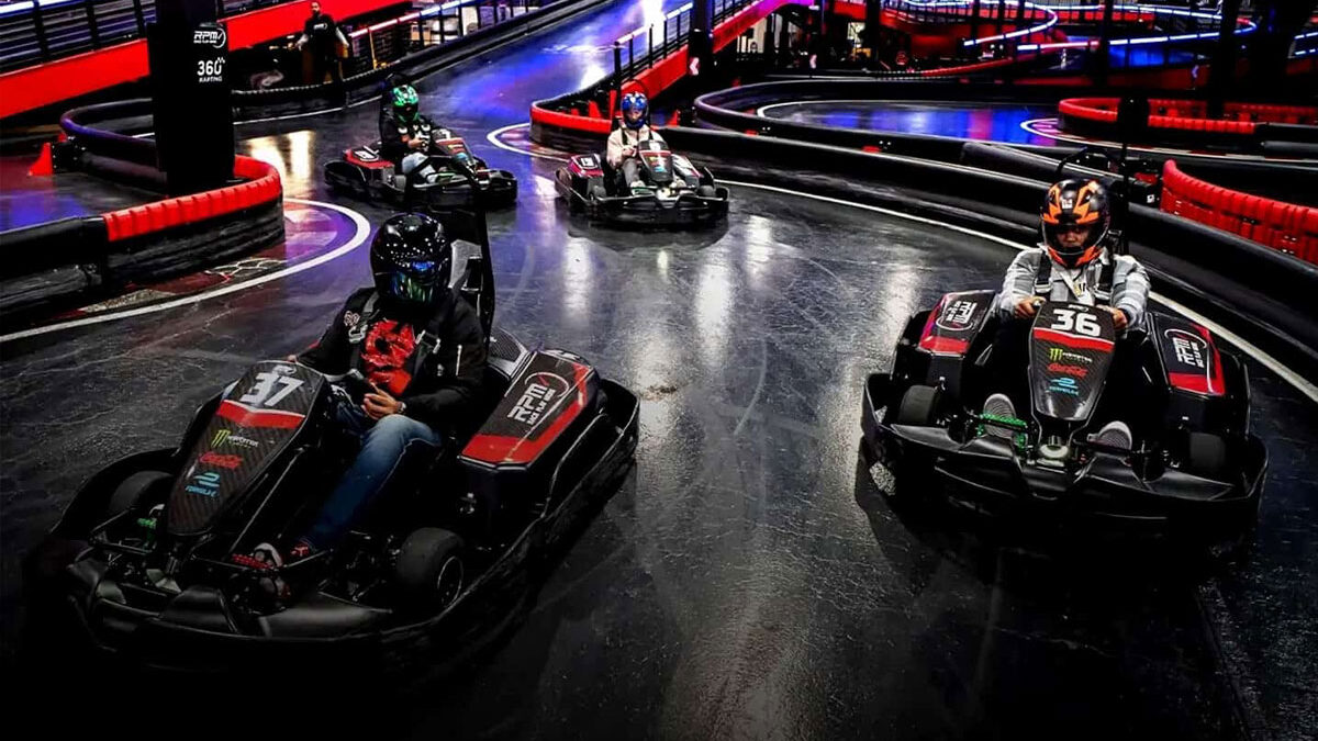 Several people in helmets driving go-carts