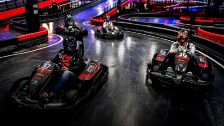 Several people in helmets driving go-carts