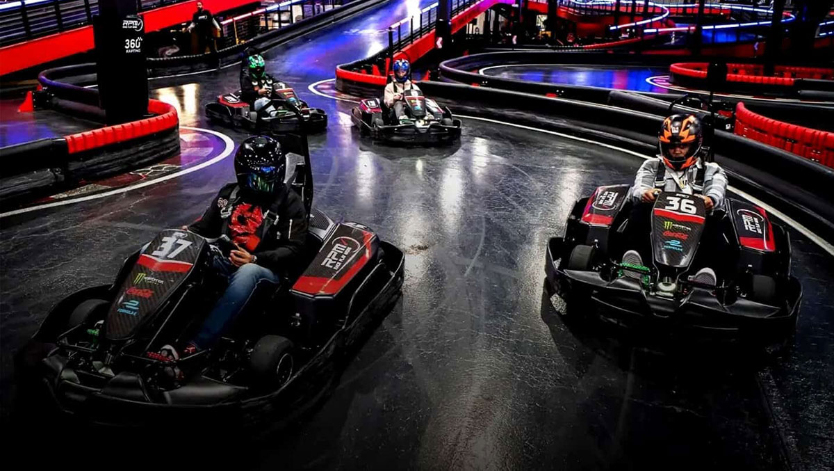 Several people in helmets driving go-carts