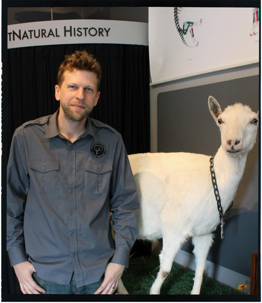 Richard Pell standing next to a goat in front of Post Natural History museum sign 