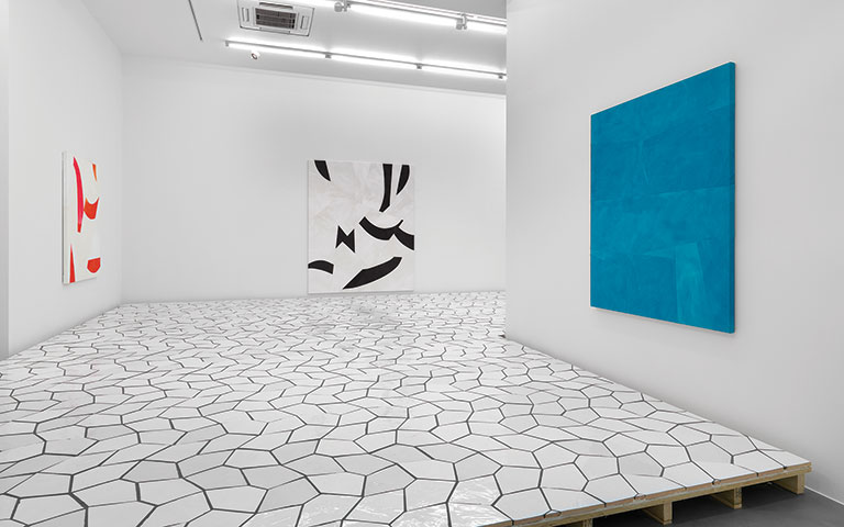 Installation view of artist's work with white tiles covering a floor.