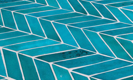 close-up view of blue terra cotta tile laid in a herring bone pattern.