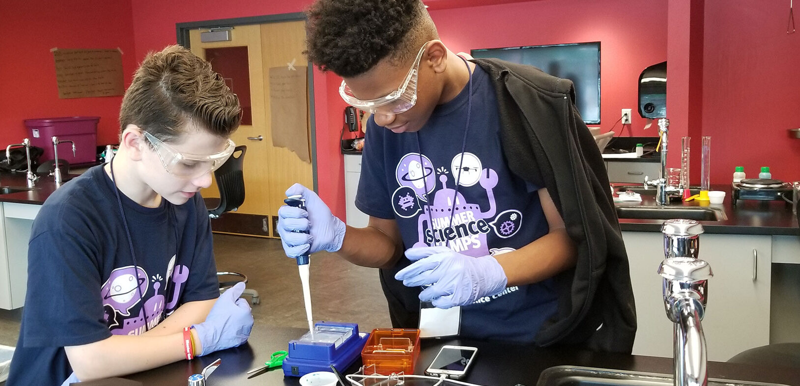 two young boys, wearing goggles, andworking on a science experiment in a high-tech classroom