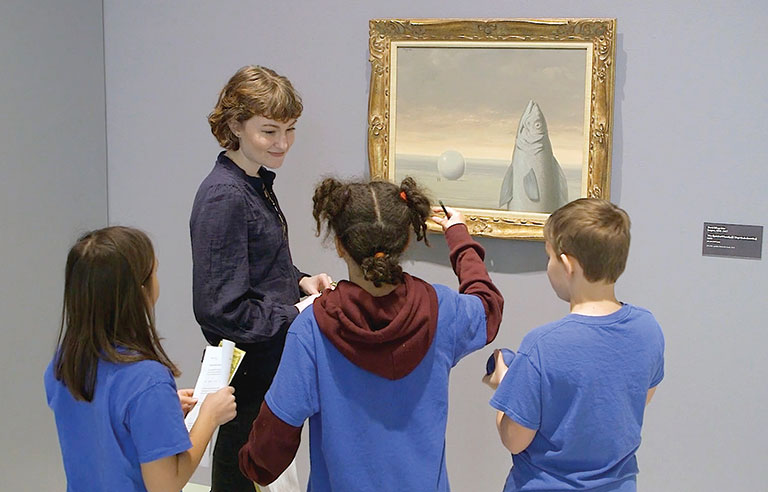 An art educator with a group of students in an art gallery.