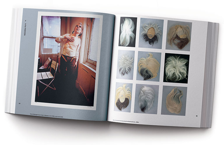 A is for Archive book open to a spread showing Andy Warhol's wig collection and a photo of him wearing a corset exposing scars from a surgery from being shot.