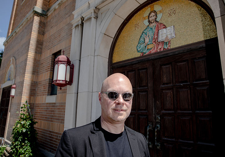 A man standing in front of the doors of a church.