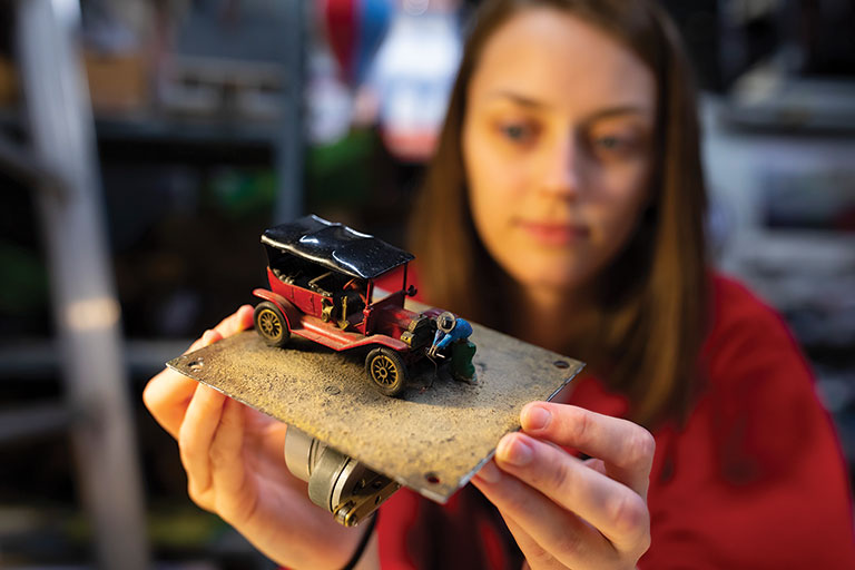 A young girl holding a miniature mechanical figure.