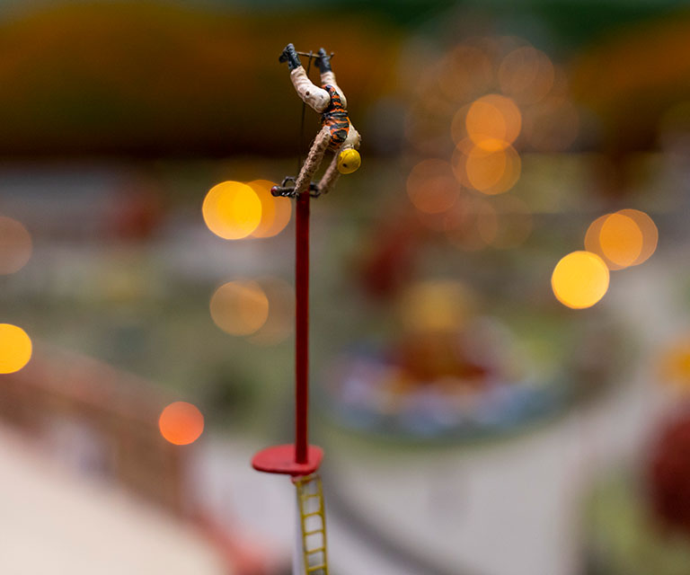A miniature figure of an acrobat doing a handstand on a pole.