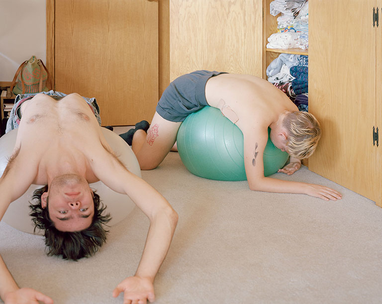 Two young people laying across large rubber balls.