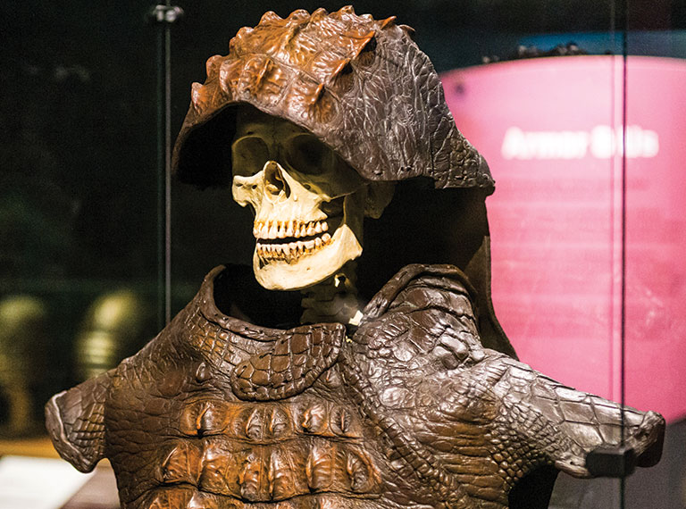 A human skeleton wearing a suit of armor made from crocodile skin