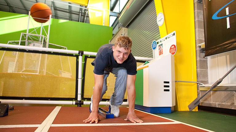 A teen age boy in the starting position to run a race