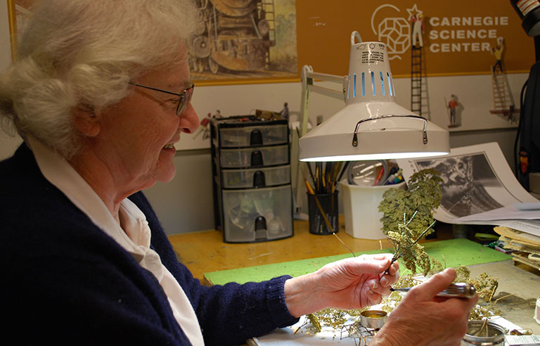 A woman working at a table making miniature trees