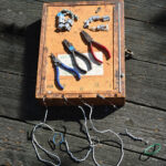 A hand-made banding box with bands and tools set out on top of it.