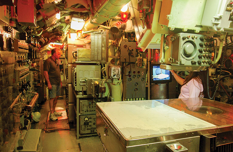 Two people in the map room area of a submarine.