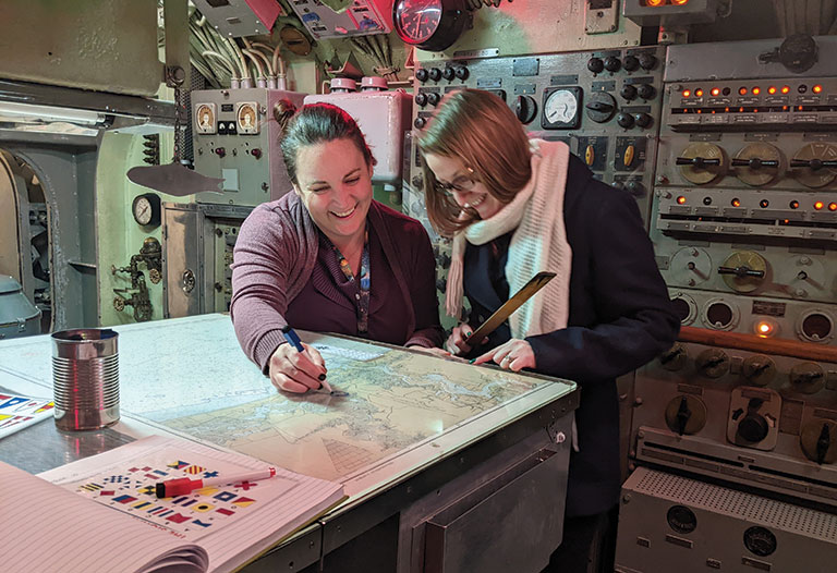 Two people looking at documents on a submarine during an escape room game.