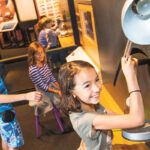 A group of children exploring an exhibit of a lamp.