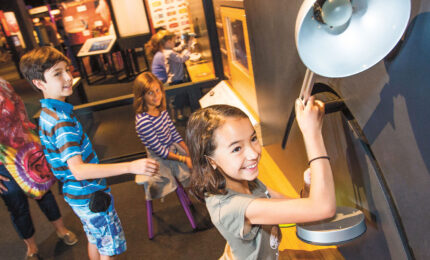 A group of children exploring an exhibit of a lamp.