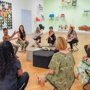 A group of teachers sitting in a circle, talking and laughing.