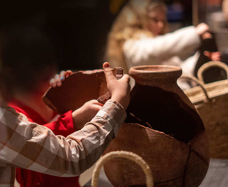 Two children putting together a puzzle of an ancient Egyptian pot.