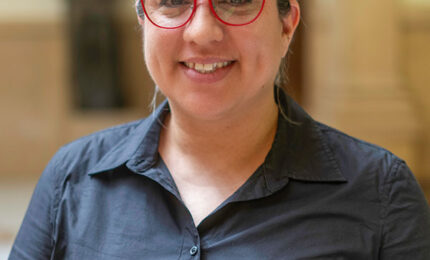 A woman wearing red glasses and a black shirt posing for a photo.