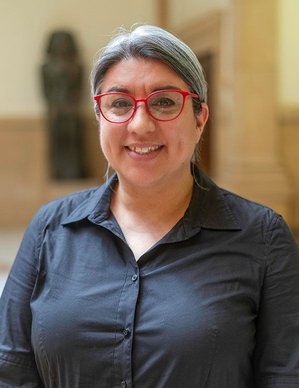 A woman wearing red glasses and a black shirt posing for a photo.