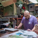 Three people working together at a table inside of a submarine.