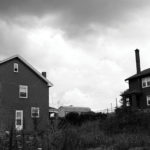 A black and white photo of two abandoned homes