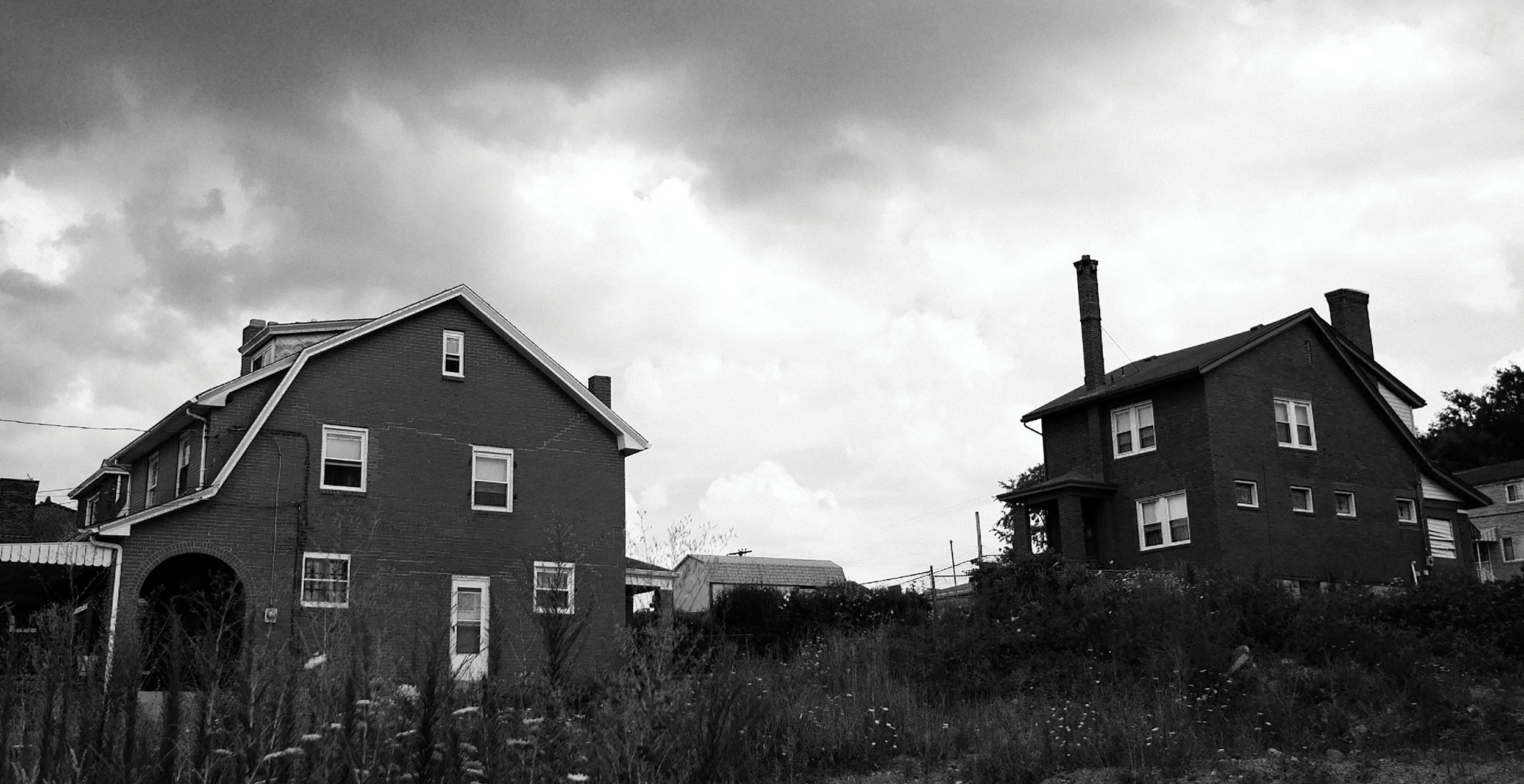 A black and white photo of two abandoned homes