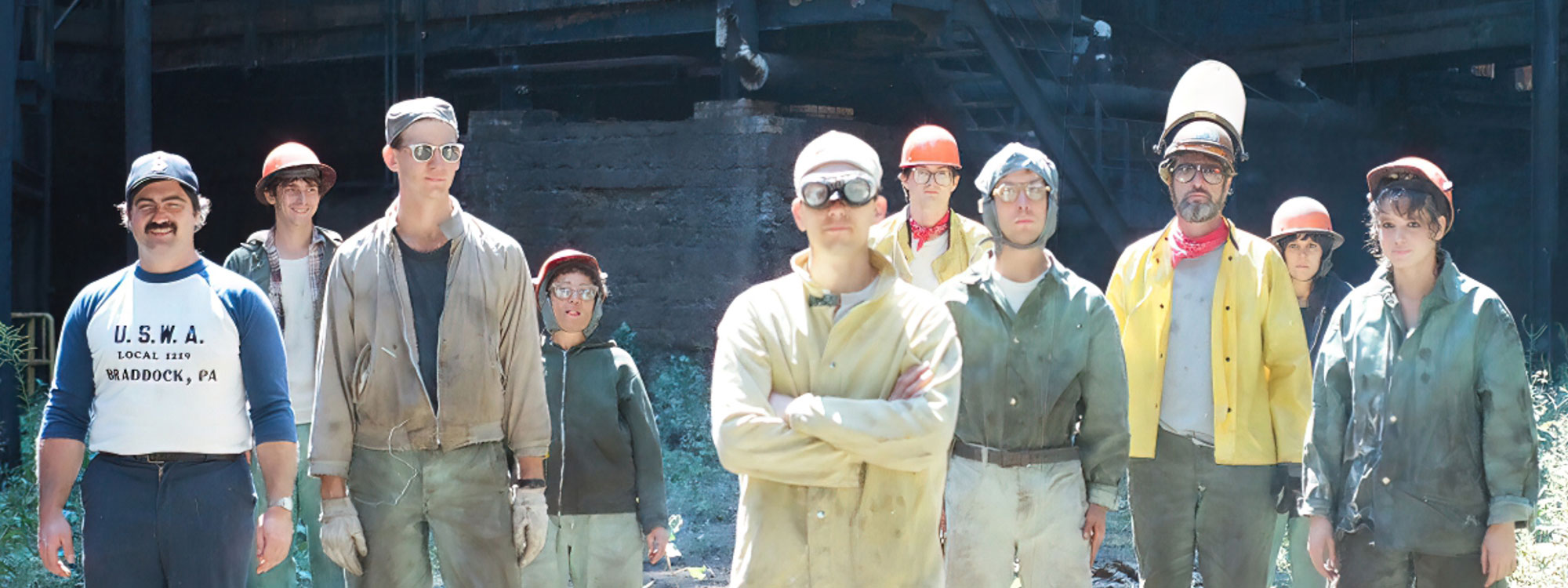 A group of Steelworkers posing with a steelmill in the background